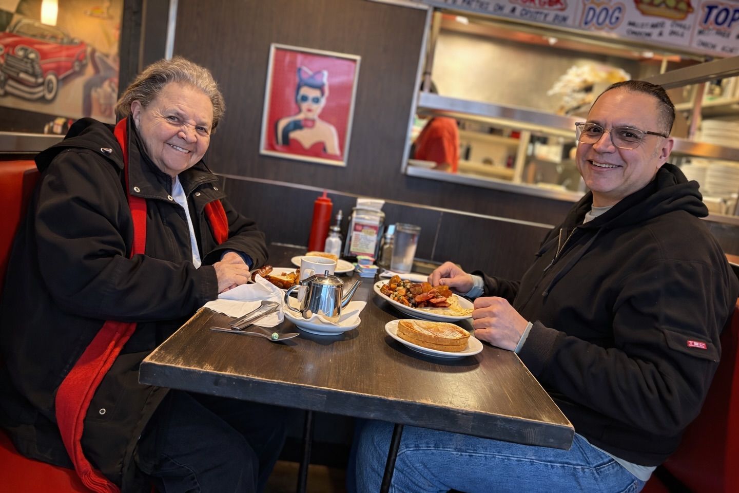 A woman and man sit with breakfast plates at a diner table